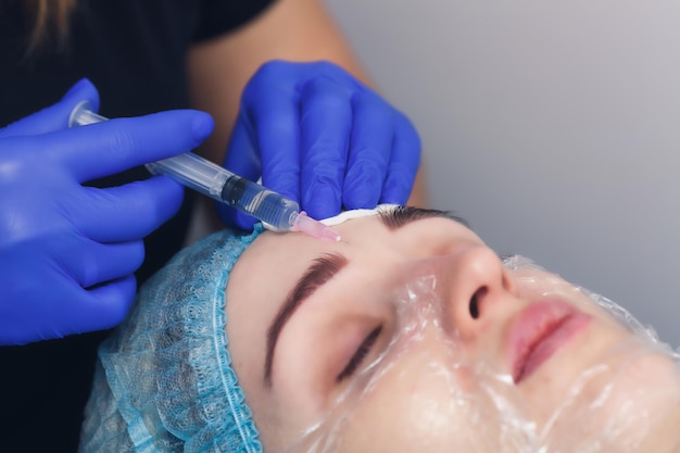 O cosmetologista faz uma injeção de preparação de mesoterapia na pele do rosto