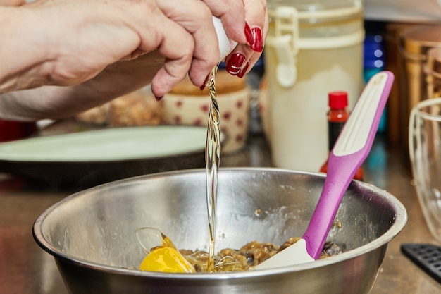 O cozinheiro adiciona um ovo à tigela de ingredientes para preparar o prato