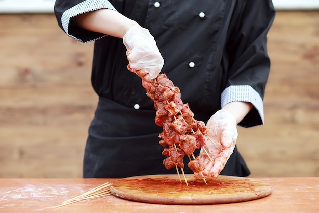 O cozinheiro corta carne para assar churrasco na mesa