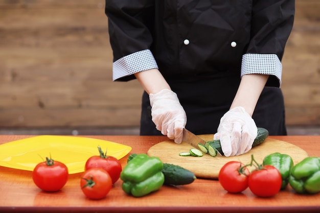 O cozinheiro corta legumes frescos da fazenda para o jantar na mesa