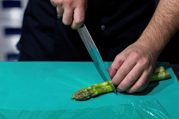 O cozinheiro cortando aspargos Cortando legumes com uma faca