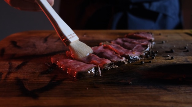 Foto o cozinheiro engorda os pedaços de carne fatiada com óleo de oliva antes de os servir