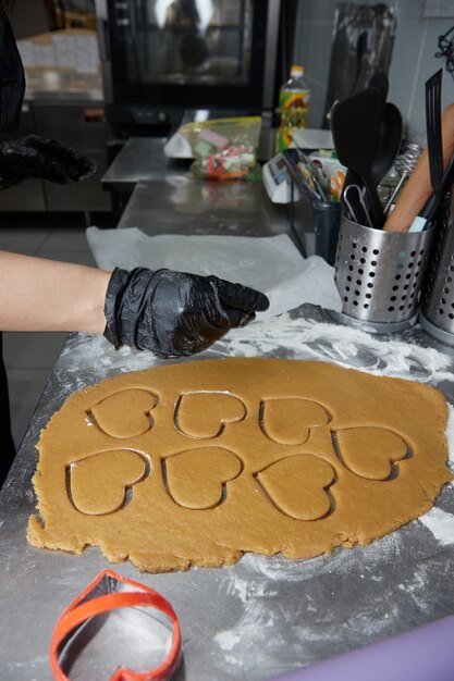 O cozinheiro faz biscoitos com as mãos enluvadas e coloca os biscoitos prontos no papel