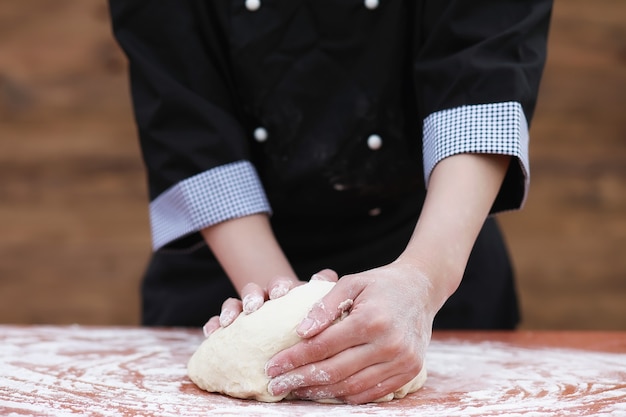 O cozinheiro faz farinha com farinha para assar na mesa