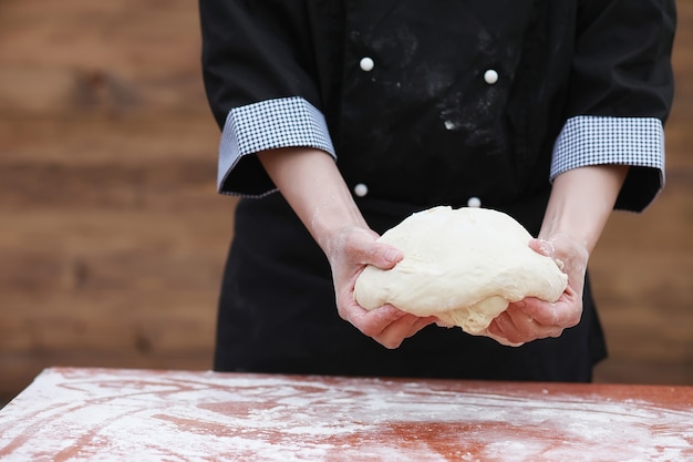 O cozinheiro faz farinha com farinha para assar na mesa