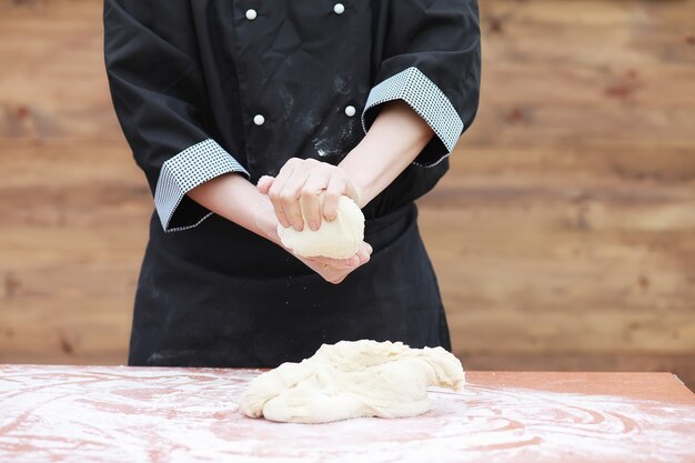 O cozinheiro faz farinha de farinha para assar na mesa