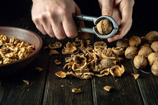 O cozinheiro limpa as nozes na mesa da cozinha para uso na culinária