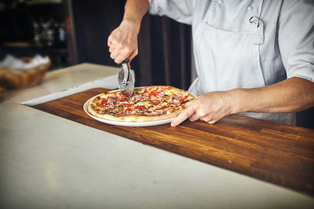 O cozinheiro mantém uma pizza grande.