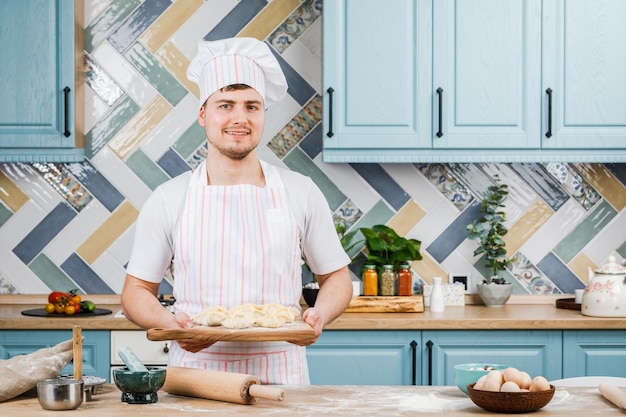 O cozinheiro na cozinha segura bolinhos nas mãos e aponta para eles com a mão O conceito de cozinhar