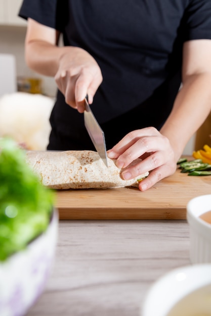 O cozinheiro picou o burrito no chopping.