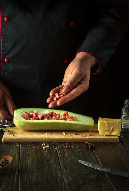 O cozinheiro prepara barcos de abóbora recheados com carne picada e legumes na mesa da cozinha O conceito de deliciosa comida nacional zucchini para o almoço