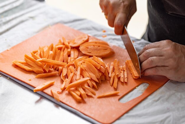 O cozinheiro profissional está cortando cenouras