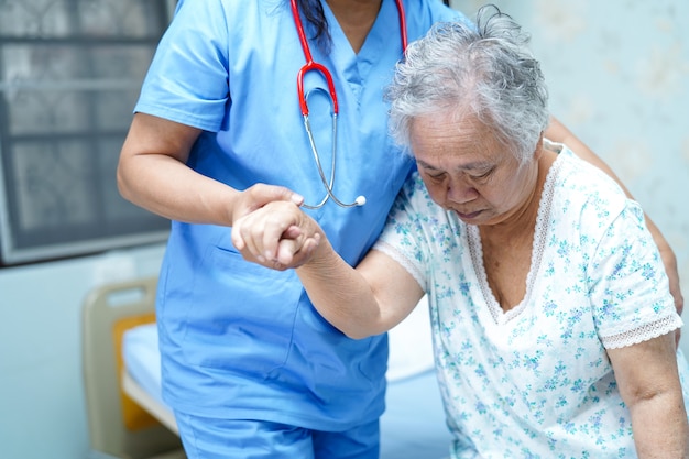 O cuidado asiático do doutor do fisioterapeuta da enfermeira, ajuda e apoia o paciente idoso da mulher da senhora idosa.