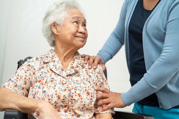 O cuidador ajuda a paciente idosa asiática com amor, cuidado, incentivo e empatia no hospital de enfermagem, conceito médico forte e saudável