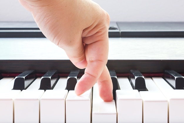 O dedo da mulher que aponta na chave do piano.