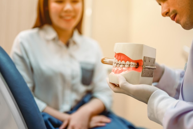 O dentista apontou o modelo dentário para explicar os pacientes para exame e atendimento odontológico na clínica Ferramentas e equipamentos odontológicos