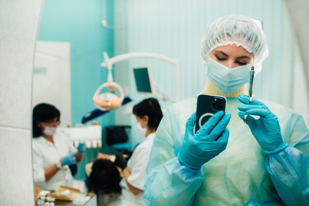 O dentista com máscara protetora fica ao lado do paciente e tira uma foto após o trabalho.