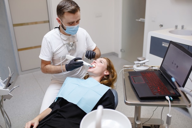 O dentista escaneia os dentes do paciente com um scanner 3D.