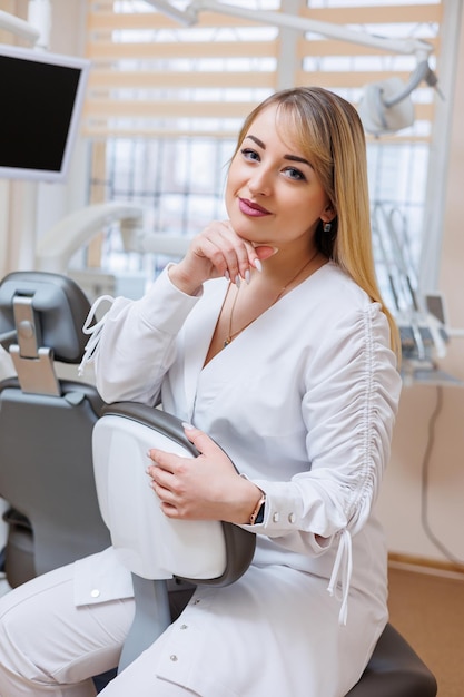 O dentista está em seu consultório odontológico Mulher dentista de jaleco branco Consultório odontológico