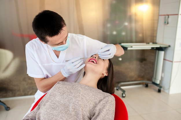 O dentista está tratando os dentes com uma linda garota.