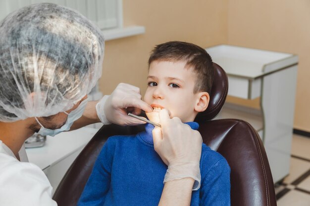 O dentista examina os dentes de um menino um paciente em uma clínica odontológica