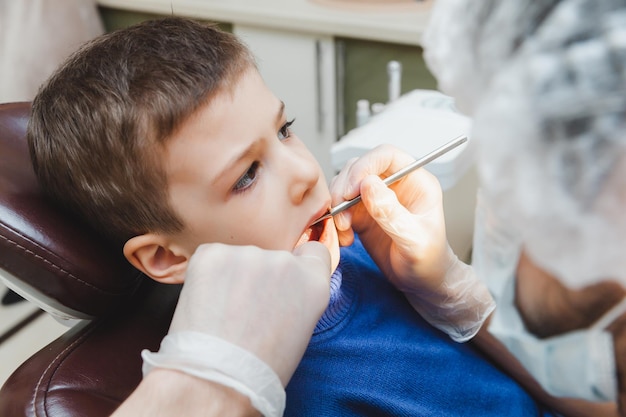 O dentista examina os dentes de um menino um paciente em uma clínica odontológica