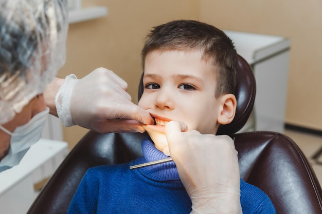 O dentista examina os dentes de um menino um paciente em uma clínica odontológica