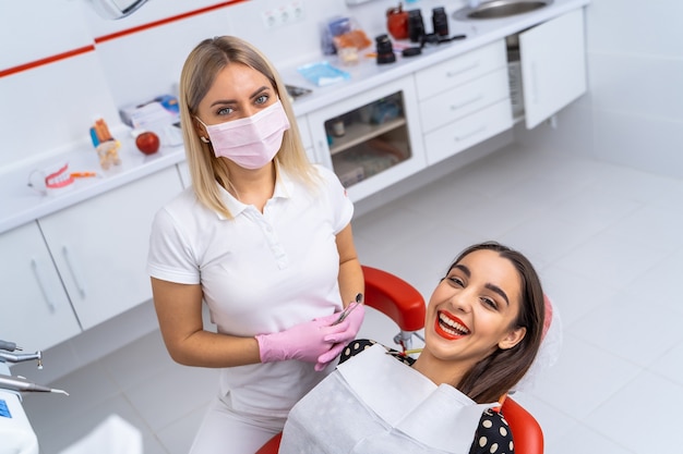 O dentista examina os dentes do paciente para o tratamento posterior. Gabinete de estomatologia moderno.