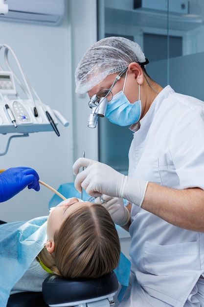 O dentista examina os dentes do paciente usando equipamentos odontológicos. equipamento médico moderno. anestesia dos dentes com anestesia local. o conceito de tratamento oral. fechar-se. foco seletivo.