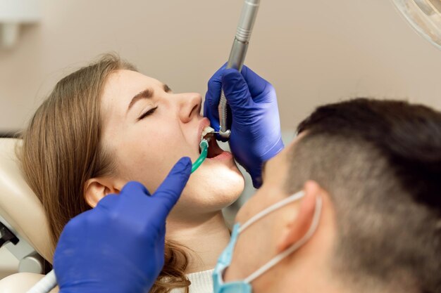 O dentista examina os dentes do pacienteclose da garota de tratamento odontológico na consulta médica em uma clínica odontológica tratamento odontológico de cárie
