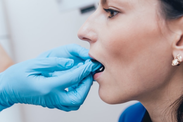 Foto o dentista faz a imagem do raio x para a jovem mulher na clínica dental. visando radiografia dentária.