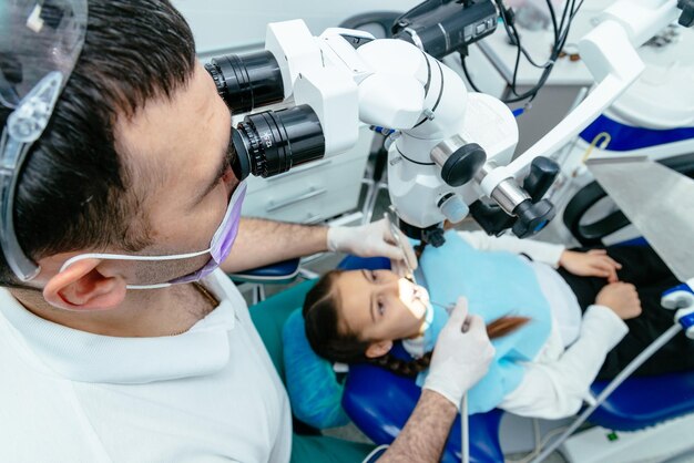 O dentista inspeciona os dentes com um microscópio