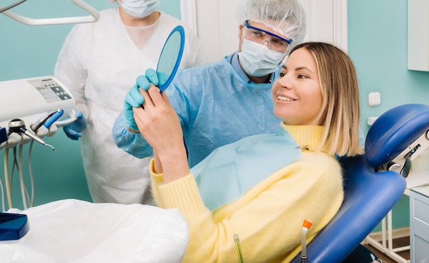 O dentista mostra ao cliente o resultado de seu trabalho no espelho.