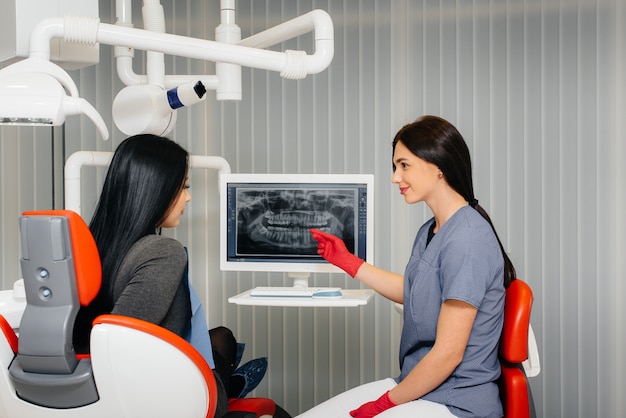 O dentista mostra uma imagem dos dentes do paciente e informa o tratamento necessário. odontologia, saúde.