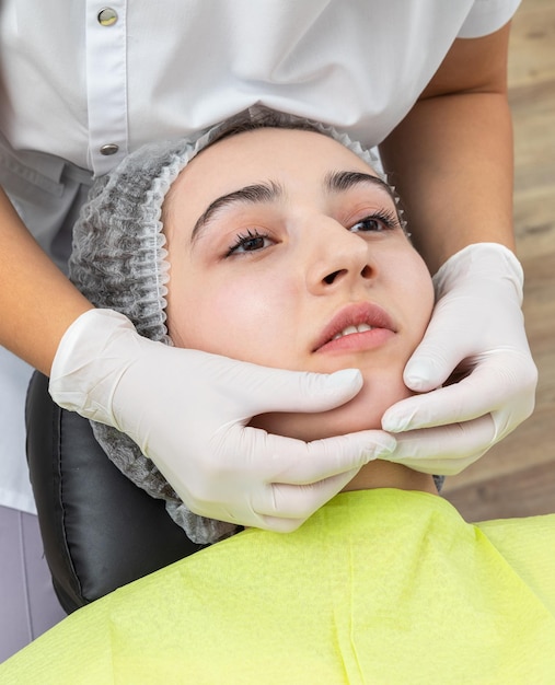 O dentista olha para a mandíbula de uma paciente do sexo feminino a verificar a mordida