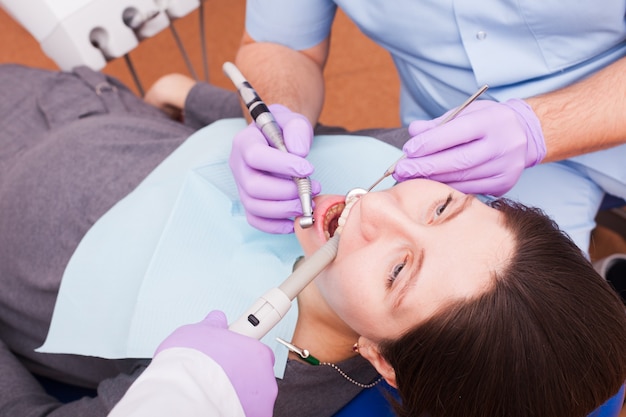 O dentista trata os dentes com a ajuda de instrumentos odontológicos. Paciente grávida