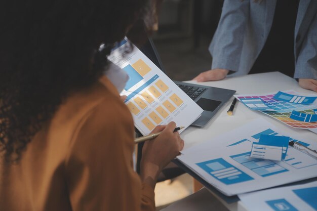 O desenvolvedor de ux e o designer de interface do usuário usam o brainstorming de realidade aumentada sobre o design de wireframe da interface de aplicativo móvel na mesa do escritório modernoAgência de desenvolvimento digital criativo