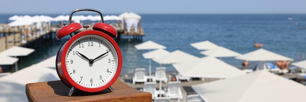 O despertador vermelho está de encontro ao conceito de férias de verão praia e mar