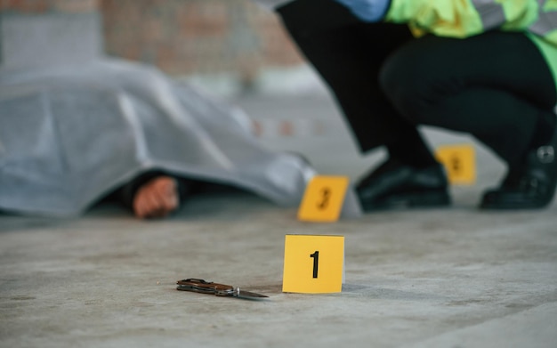 O detective está a recolher provas numa cena de crime perto de um cadáver no local de construção.