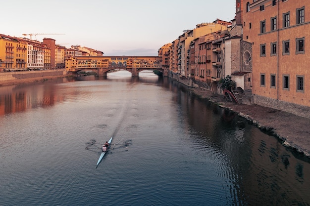 O dique do rio Arno com a ponte Ponte Vecchio e os edifícios da cidade velha ao pôr-do-sol em Florença, Itália