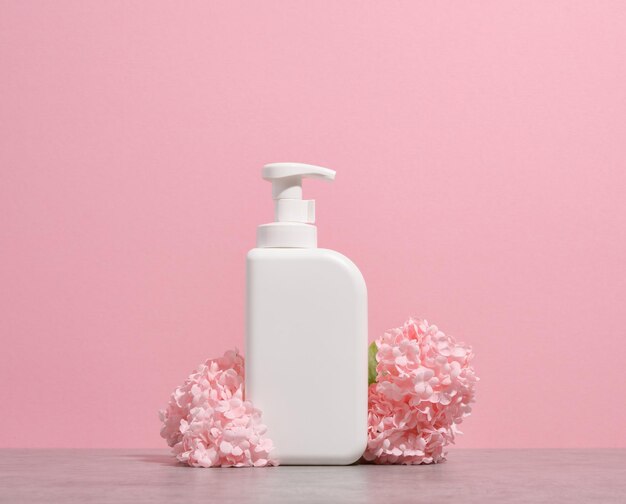 O dispensador de gel de lavar louça branco entre as lindas flores da primavera Lavando pratos na cozinha