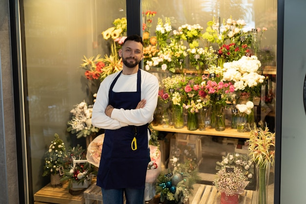 O dono de uma boutique de buquês ao lado de uma geladeira com flores frescas