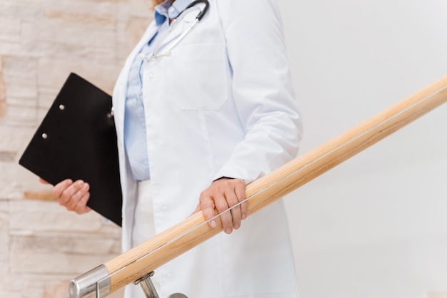 O doutor está aqui. close de uma médica de uniforme branco segurando uma prancheta enquanto desce as escadas