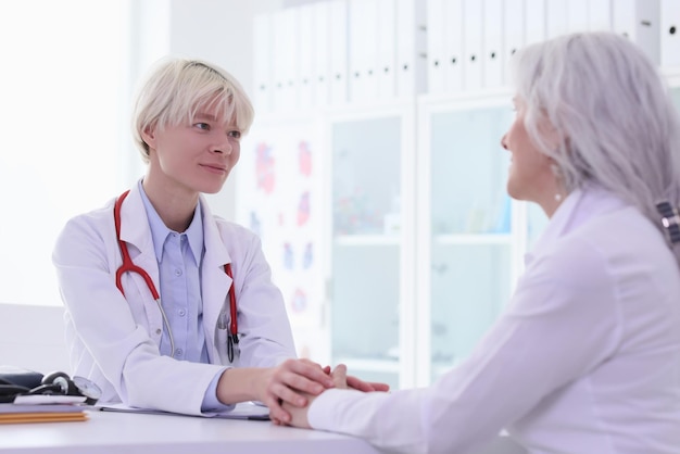 O doutor guarda as mãos do paciente durante a consulta no hospital