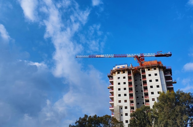 O edifício está em construção por um guindaste em Israel contra o céu azul