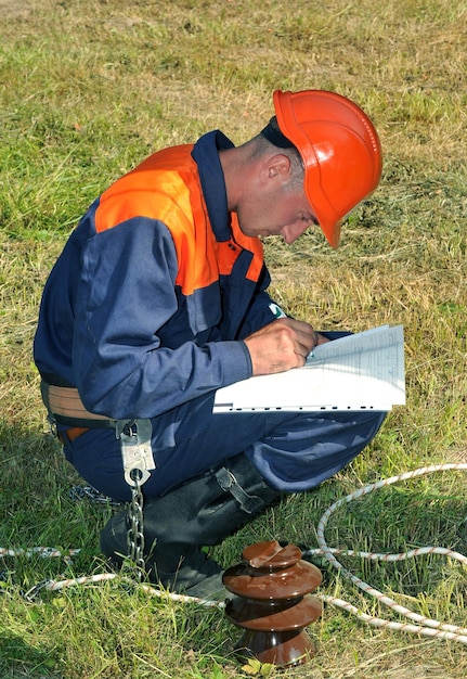 Foto o eletricista estuda a tarefa técnica para realizar trabalhos de reparo na substituição do isolador