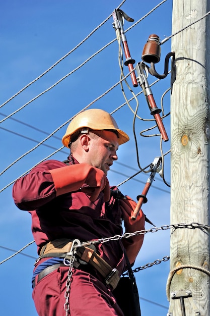 O eletricista instala o aterramento na linha de energia antes de repará-la.