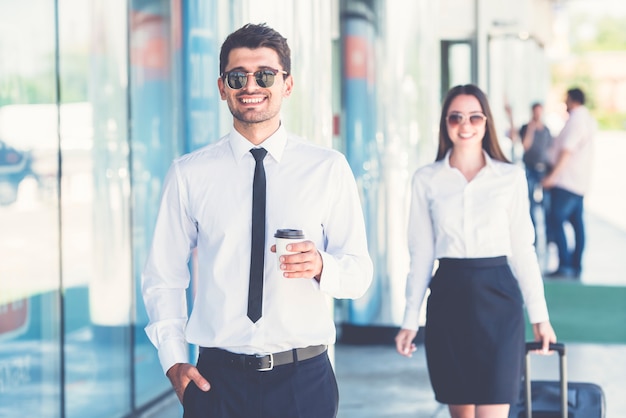 O empresário bonitão fica perto da mulher com uma mala