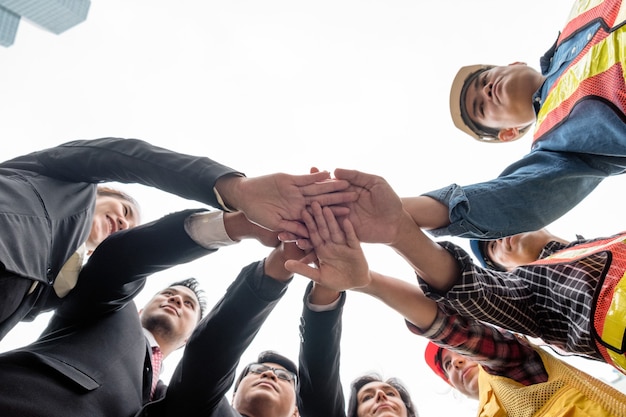 O empresário com o grupo de engenheiros toma as mãos da coordenação empilhadas, perspectiva de baixo ângulo