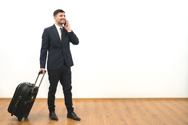 O empresário com uma bolsa de telefones no fundo da parede branca